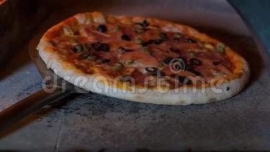 意大利披萨和西红柿是在烤箱里煮的，餐馆厨师在餐馆的木头烤箱里拿披萨。